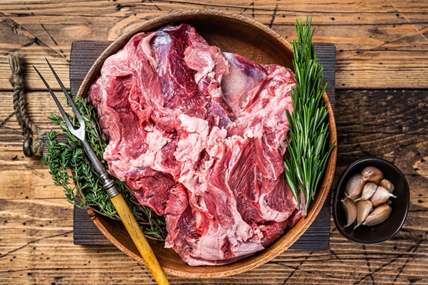 boneless raw mutton lamb shoulder meat in wooden plate with herbs - Баранина по-индийски
