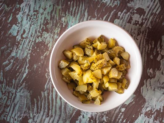 chopped pickled cucumbers in a deep white plate for making salad top view - Куриный рассольник