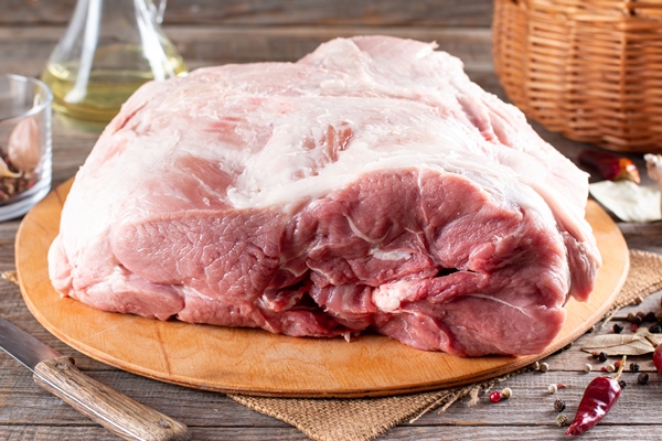 raw pork meat on wooden cutting board at kitchen table for cooking pork steak roasted or grilled with ingredients herb and spices fresh pork raw pork ham - Буженина домашняя