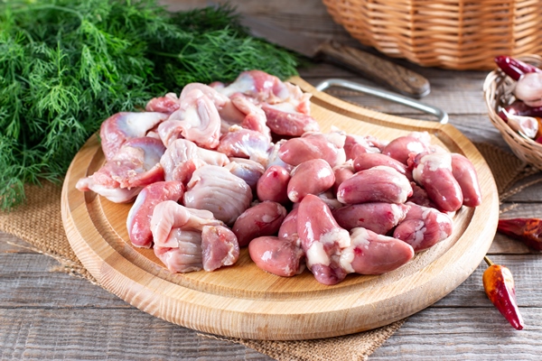 raw uncooked chicken gizzards chicken hearts on wooden cutting board on a wooden table concept of healthy eating - Куриный рассольник