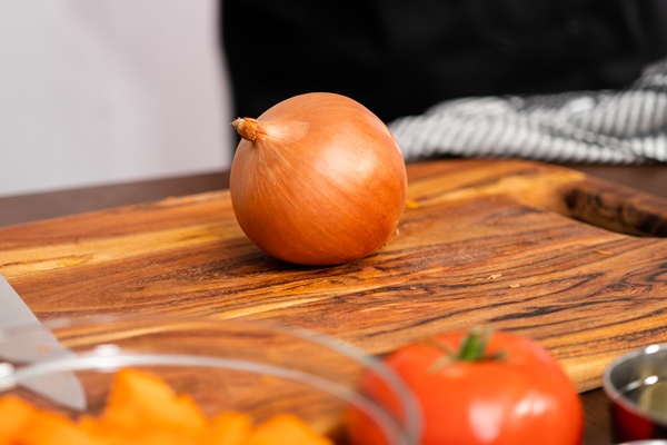 slicing yellow onion on wood cutting board - Турецкая запеканка с кебабом