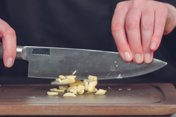 step by step dicing organic garlic on wood cutting board - Буженина домашняя