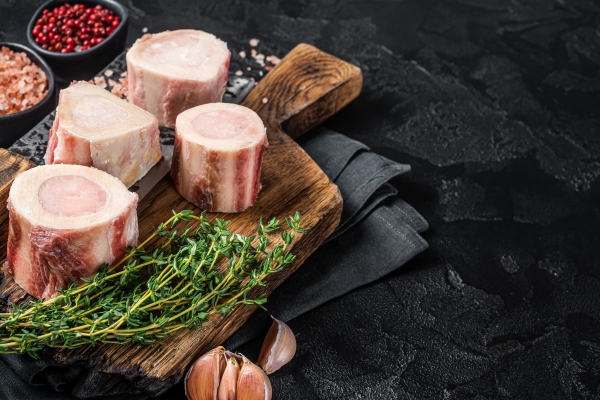 uncooked raw veal marrow bones on butcher board with meat cleaver black background top view copy space - Французский соус "Борделез"