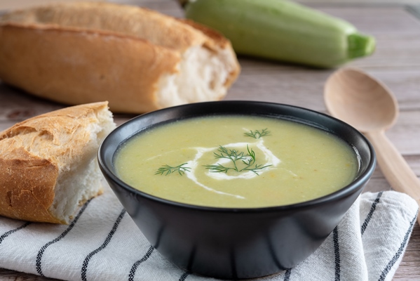 vegetable squash puree soup a whole zucchini slices of bread and a wooden spoon on a wooden background side view - Чесночный суп-пюре
