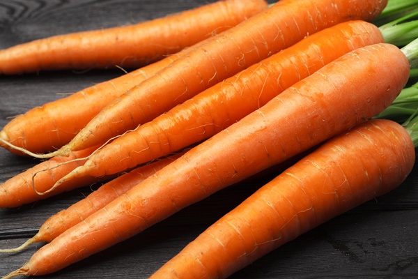 bunch of fresh carrots with green leaves on wooden table - Пюре из курицы и риса с морковью и яблоком (питание детей до 1 года)