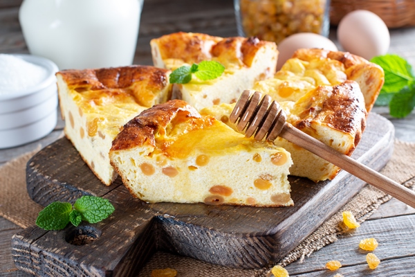 cottage cheese casserole with raisins on wooden background - Творожная запеканка с манкой, изюмом и молоком