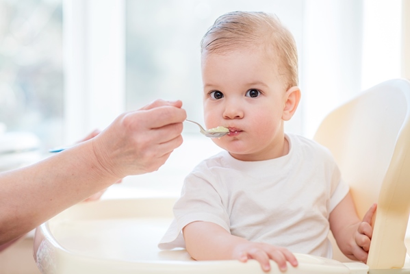 grandmother gives baby food from a spoon - Овощной суп с сыром для детей до 1 года