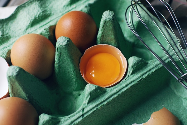 group of raw brown chicken eggs in green paper tray on rustic wooden table fresh half cracked egg - Суфле из хека для питания детей до 1 года