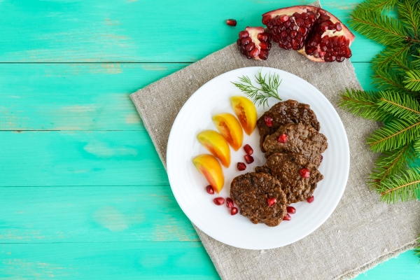 juicy liver cutlets with pomegranate seeds on a white plate the top view - Печёночные оладьи