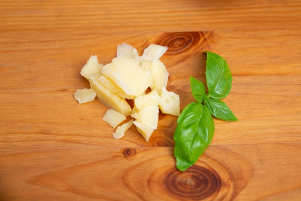 pieces of parmesan and green basil on wooden table - Овощной суп с сыром для детей до 1 года