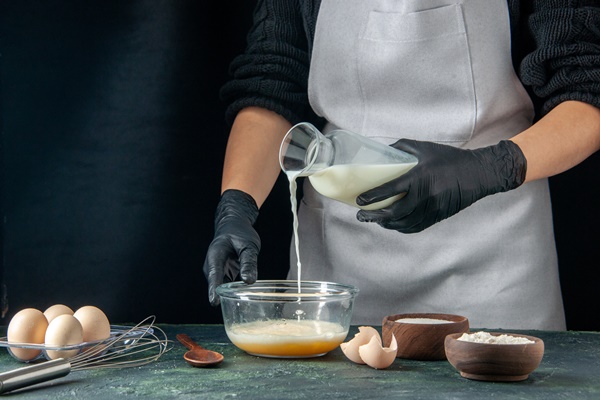 front view female cook pouring milk into eggs on a dark pastry cake pie worker dough cuisine job hotcakes - Венские вафли в электровафельнице