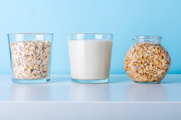 glass of oat flake vegetable milk and jar with soaking oatmeal - Постный смузи-боул из банана, чёрной смородины и клубники