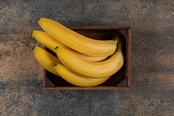 ripe bananas in the box on the marble surface - Постный смузи-боул с бананом, киви, клубникой, голубикой