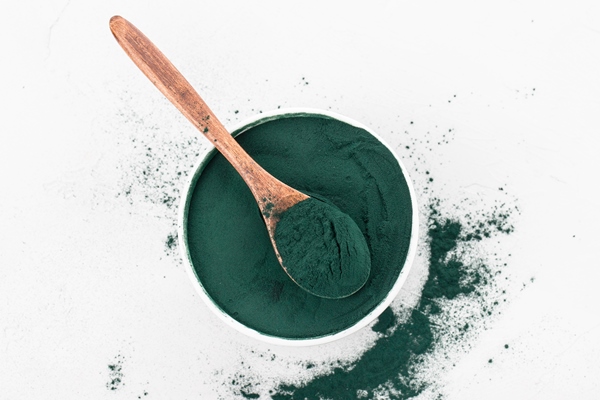 spirulina powder in a white bowl with spoon - Постный смузи-боул с зелёной гречкой