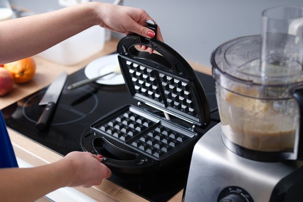woman hand opening lid of multibaker to make viennese waffles near food processor closeup - Венские вафли в электровафельнице