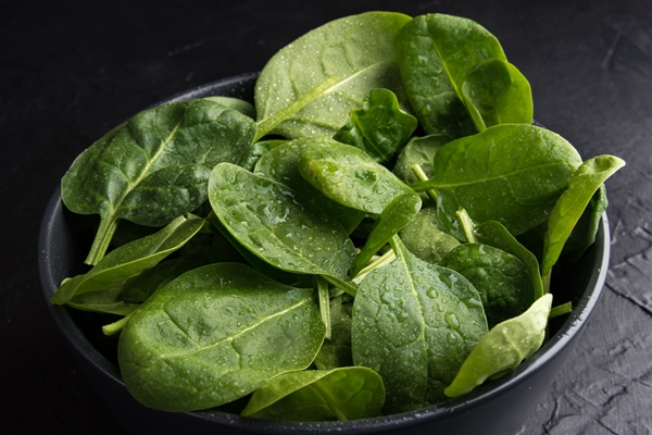 baby spinach leaves with water drops in a ceramicn plate on a black surface - Смузи-боул со шпинатом и авокадо