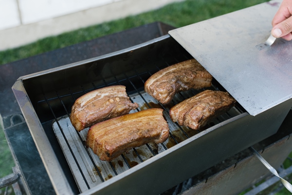 bacon is smoked in a metal smokehouse in the open air - Консервирование пищевых продуктов