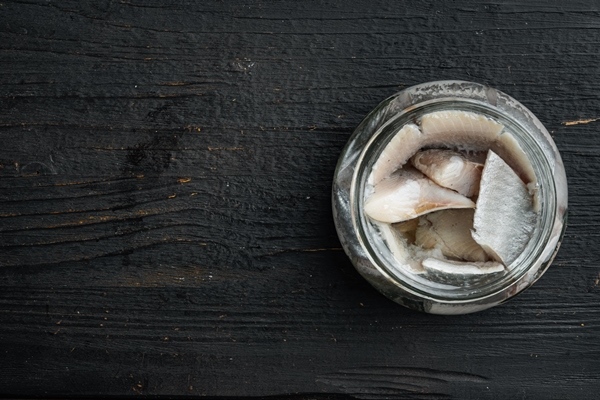 canned herring fish preserves set in glass jar on black wooden table - Консервирование пищевых продуктов