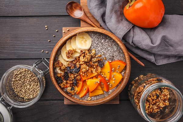 chia pudding with banana persimmon and granola dark wooden background top view copy space - Смузи-боул с хурмой и семенами чиа