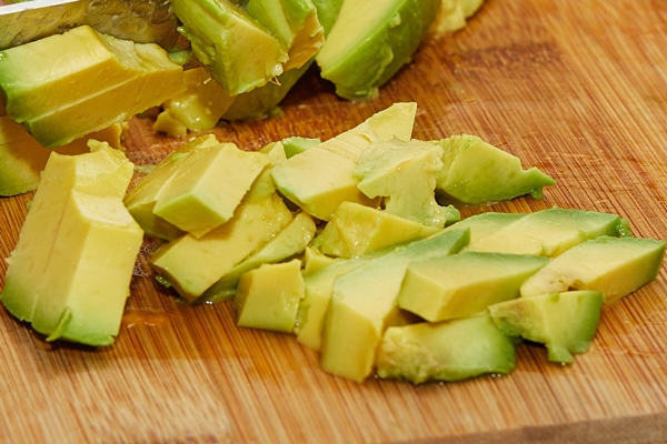 cook cuts ripe avocado into slices for salad making - Смузи-боул со шпинатом и авокадо