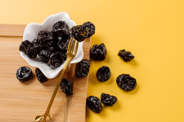 dried prunes on a wooden board on a yellow background - Заварная пасха диетическая (при сахарном диабете)