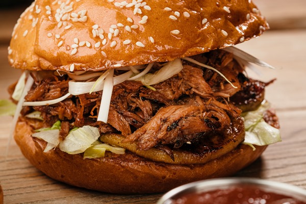 juicy burger with duck confit pear cucumber leek hoisin sauce and peking duck on a wooden table - Утиное конфи