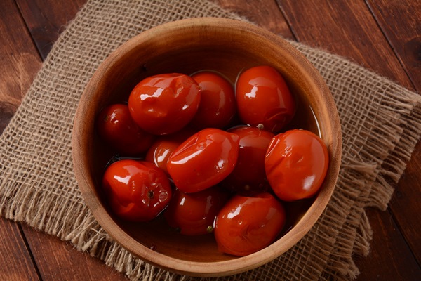 pickled red tomatoes in bowl on wooden background rustic style - Консервирование пищевых продуктов