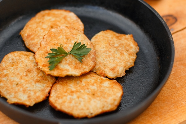 potato pancakes on a cast iron frying pan with onions on a white wooden table 1 - Драники с апельсиново-клюквенным соусом