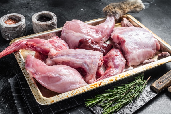 raw wild hare slices legs fresh game meat in steel tray with herb black background top view - Мясной пасхальный стол: кролик, тушённый в сметане