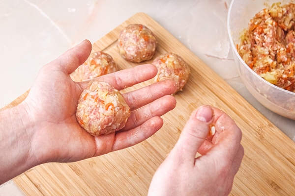 a man sculpts lazy cabbage rolls from minced meat cabbage rice the man is forming meat balls - Котлеты из риса и консервов