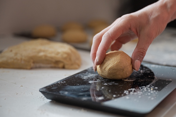 closeup of female hand weighing home made pastry dough ball - Просфоры на заварной опаре
