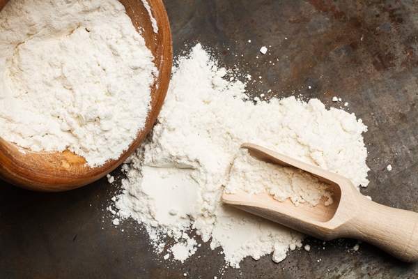 flour in a wooden bowl with a wooden spoon on a metal table - Просфоры на заварной опаре