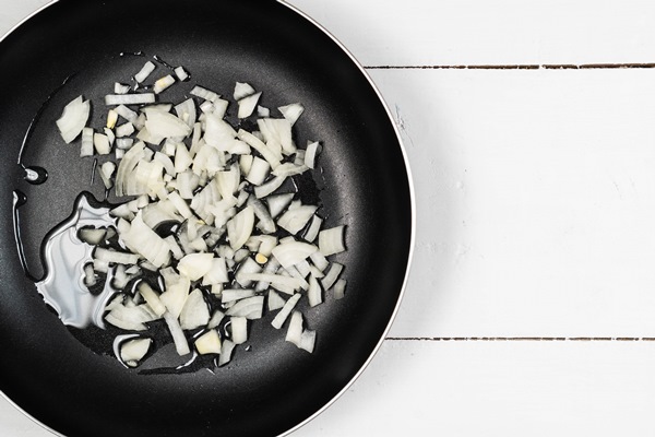 frying onions in the hot oil with copy space above white boards - Пшённая каша с луком и чесноком