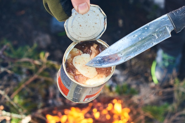 hands holding an open jar of canned meat and a knife - Борщ "Туристический" с грибами и тушёнкой