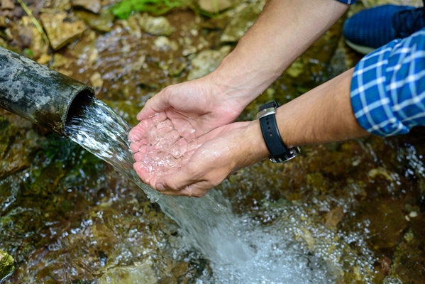 large men s hands are gaining in the palm of clean water from an underground source spring well - Рецепты выживания в лесу