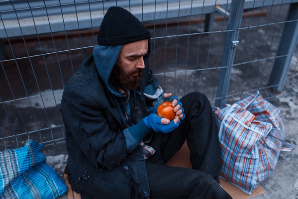 male person gives food to bearded dirty beggar on city street - Как перестать выбрасывать продукты и сократить расходы
