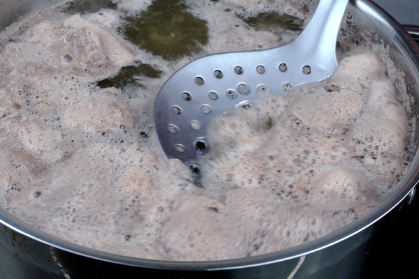 meat broth with abundant foam boils in saucepan foam is removed with metal slotted spoon - Фронтовой кулеш