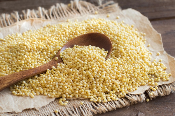 raw millet with a spoon on wooden table close up - Щи солдатские