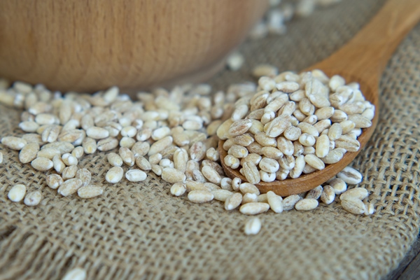 raw pearl barley in a wooden spoon spilling on an old wooden table - Каша "Остатки сладки"