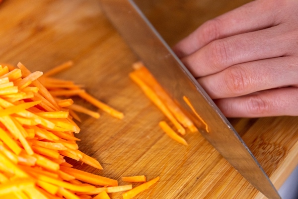 slicing carrots into strips on a cutting board - Щи солдатские
