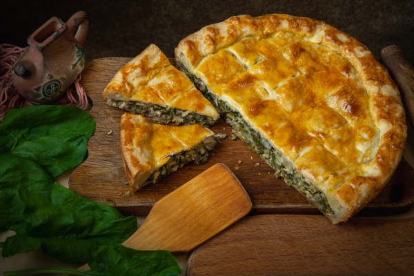 vegetable pie homemade baking with spinach and onions on a dark wooden background - Использование в пищу огородной и дикорастущей зелени