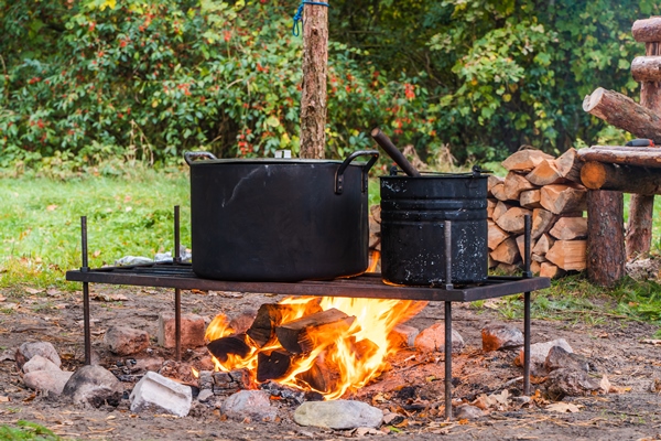 kettle over campfire cooking food in wild camping traveling and tourism concept - Овощное туристическое рагу