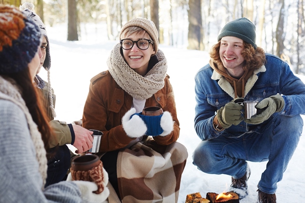 young couple enjoying drinks in winter forest - Чай "Охотничий"