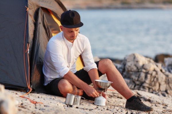 young man sitting on rocky seashore near tent setting gas tile 1208 596 - Мясо с овощами по-походному