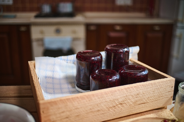 jars with berry jam stacking upside down on wooden crate standing on kitchen island - Клубничное варенье