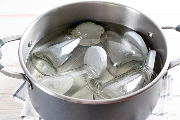 sterilizing glass jars in a steel pan steaming bubbling wather - Клубничное варенье