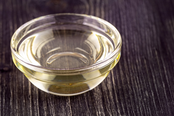 the cooking vegetable oil in a small glass cup on old wooden table - Постная шарлотка на апельсиновом соке