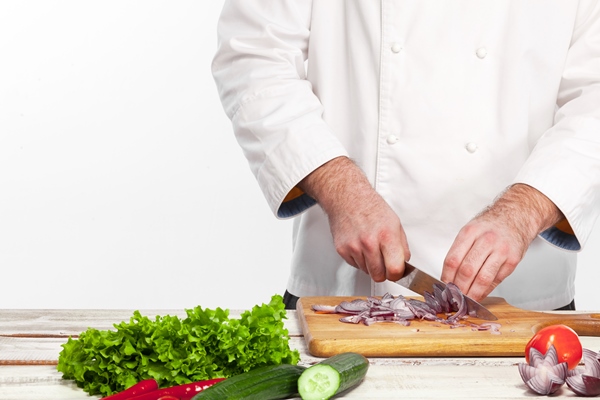 chef cutting a onion on his kitchen - Закуска из фасоли с овощами по-гречески