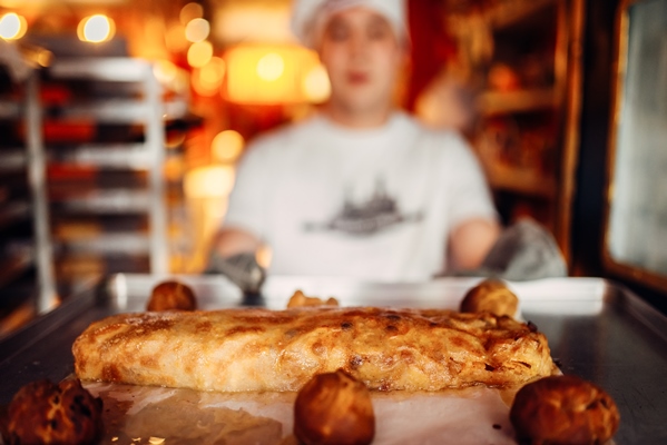 chef holds baking sheet with fresh cooked strudel - Постный штрудель с яблоками, орехами, изюмом и корицей