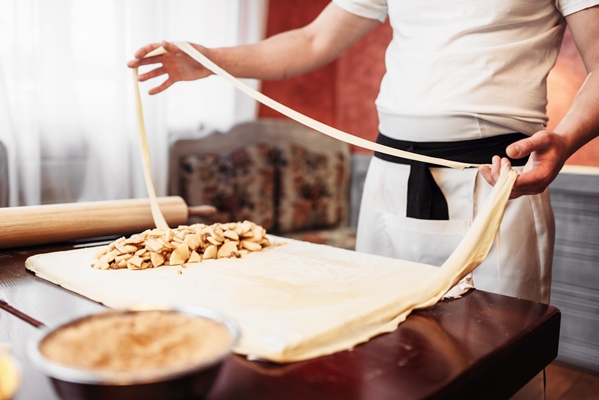 male chef prepares dough for apple strudel - Постный штрудель с яблоками, орехами, изюмом и корицей